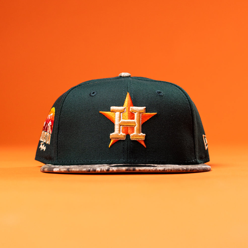 The Greenhand RTC Oil Houston Astros New Era Hat 5950 Fitted is a green fitted cap with the Astros H star logo, orange embroidery, and a patterned flat brim, shown on an orange background.
