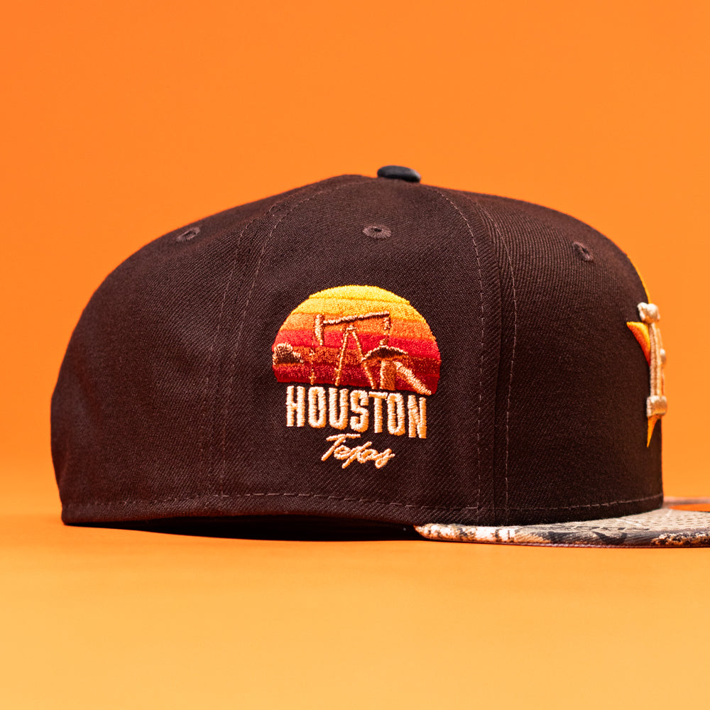 The Old Head RTC Wood Oil Houston Astros New Era Hat 5950 Fitted is a black cap featuring a sunset design, "Houston Texas" on the side, and a unique patterned brim—ideal for any Houston Astros hat collector.