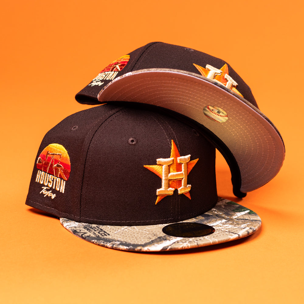 The Old Head RTC Wood Oil Houston Astros New Era Hat 5950 Fitted features a colorful embroidered logo and printed brim. Displayed on an orange background, one hat’s brim faces forward, while the other shows its unique underside design.