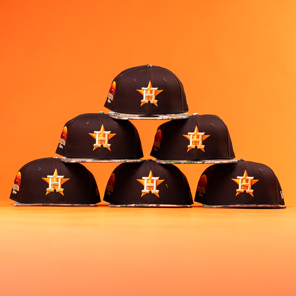 Six black Old Head RTC Wood Oil Houston Astros New Era Hat 5950 Fitted caps, each featuring an orange star with an "H," are arranged in a pyramid against an orange background.