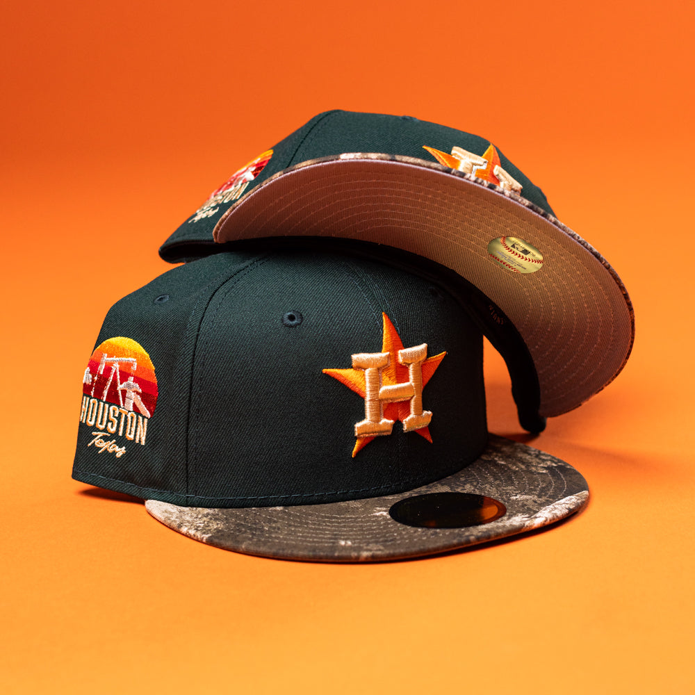 Two Greenhand RTC Oil Houston Astros New Era 5950 Fitted hats are displayed on an orange background, stacked to show both the front and underside of the brim.
