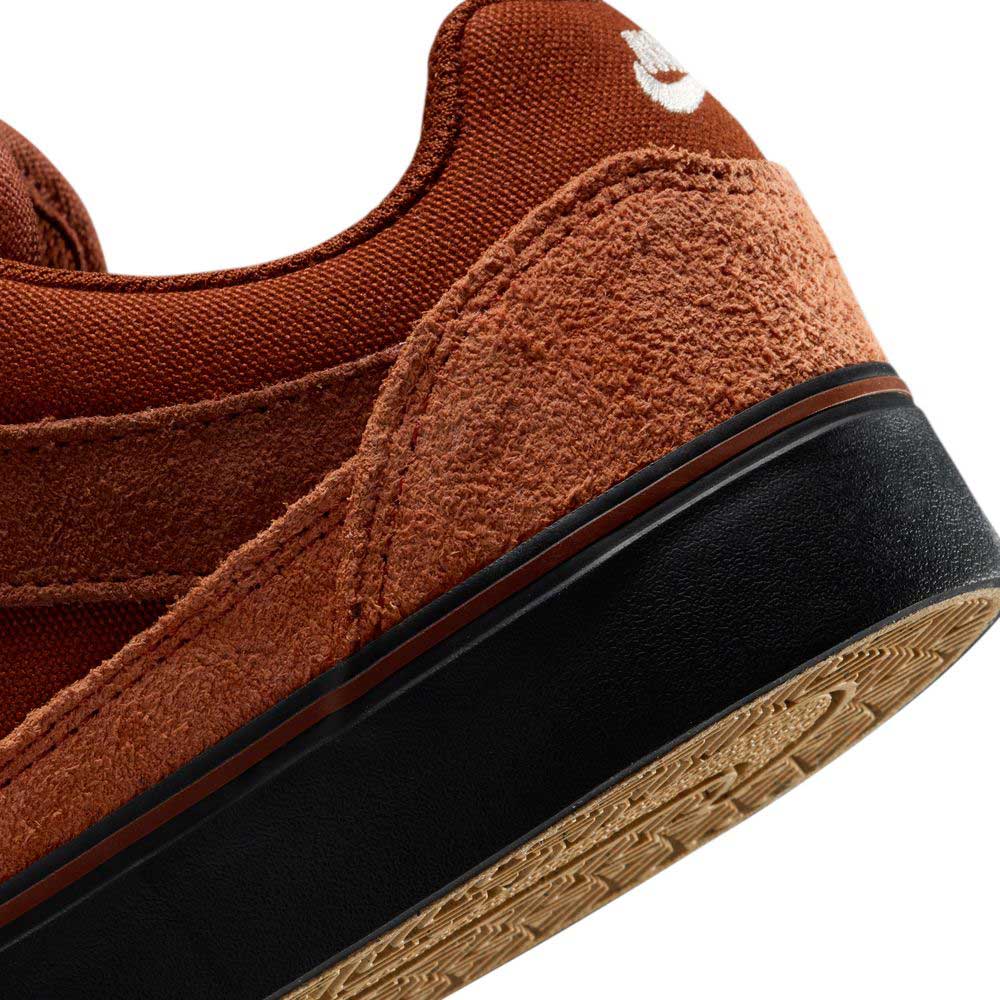 Close-up of the heel of the HF1205200 Cinnamon Light Bone YOUTH Malor GS Nike SB shoe, featuring brown suede and a black and tan rubber sole. The white logo is partly visible, showcasing the quality expected in durable skate footwear.