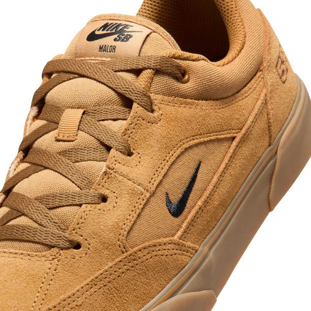 Close-up of the Nike SB Malor TE (HF3066701) skate shoes in Wheat Gum Light Brown Black White, featuring a textured, stitched tan suede upper, gum sole, brown laces, and black Nike swoosh on the side and tongue.