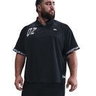 A man with a beard and mustache wears the HJ 2965010 Black Nike SB Dri-FIT Jacquard Skate Jersey, featuring white graphic details on the chest and sleeves, standing with his arms relaxed and looking to his left.
