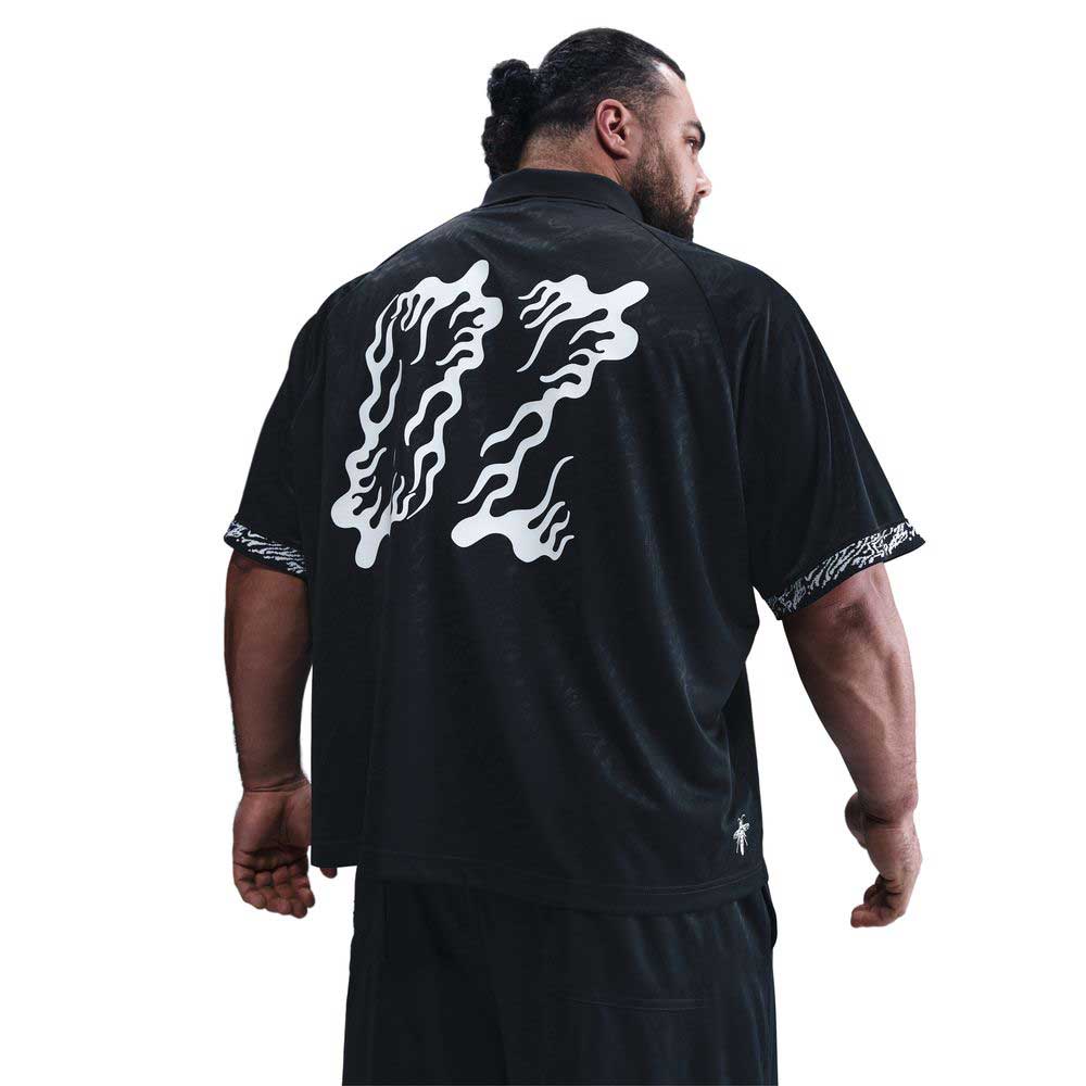 A man with a beard and ponytail faces away, wearing the HJ 2965010 Black Nike SB Dri-FIT Jacquard Skate Jersey, which features a large white wavy back design and patterned sleeve trim.