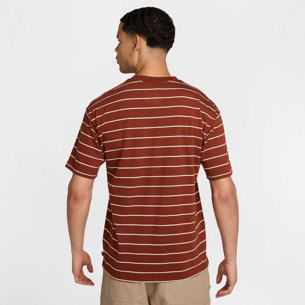 A man stands with his back to the camera, wearing the HJ0812619 U NK SB TEE M90 Maroon Red STRIPE Nike SB Skateboarding shirt and tan shorts, set against a plain white background.
