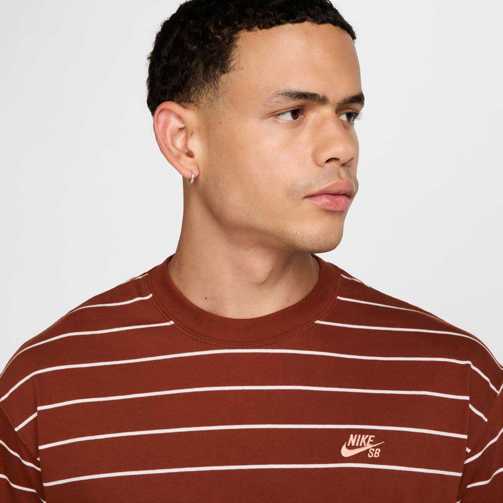 A person with short curly hair wears the HJ0812619 U NK SB TEE M90 Maroon Red STRIPE Nike SB Skateboarding shirt, looking to the side against a plain light background.
