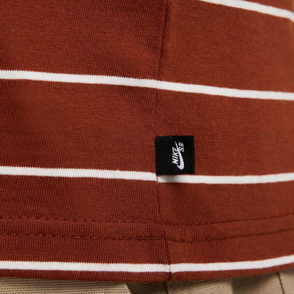 Close-up of the HJ0812619 U NK SB TEE M90 in maroon red with white stripes and a small black Nike SB Skateboarding tag near the hem.