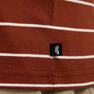 Close-up of the HJ0812619 U NK SB TEE M90 in maroon red with white stripes and a small black Nike SB Skateboarding tag near the hem.