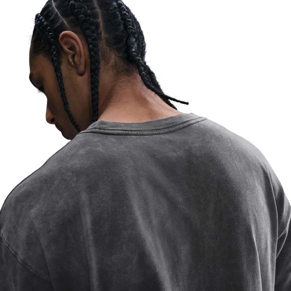 A person with braided hair is shown from behind, wearing the HJ0816060 Max 90 Skate T-Shirt SB Tee in faded gray. The loose, midweight cotton Nike SB shirt stands out against a white background, highlighting the back and shoulders.