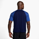 A man, back to the camera, wears the HJ2956492 Royal Blue Navy Blue Dri-Fit Knit Skate Jersey by Nike SB Skateboarding Embroidered with black shorts, set against a plain white background.