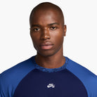 A man with a shaved head wears the HJ2956492 Royal Blue Navy Blue Dri-Fit Knit Skate Jersey by Nike SB Skateboarding, featuring embroidered details, and looks directly at the camera against a plain white background.