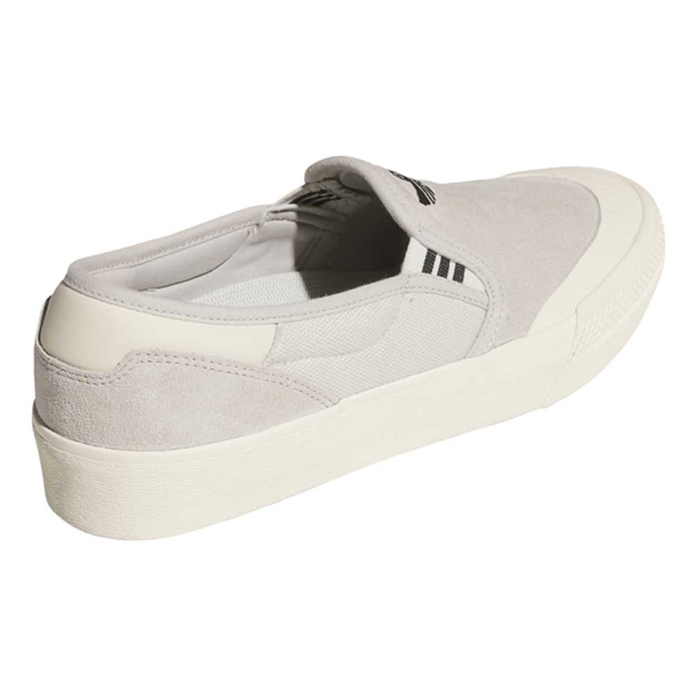 The HQ4721 Gray White Shmoofoil Slip RX Adidas Skateboarding suede shoe features a light gray slip-on design with a thick white sole, white toe cap, and subtle black stripe detail near the tongue, shown angled from the back and side.