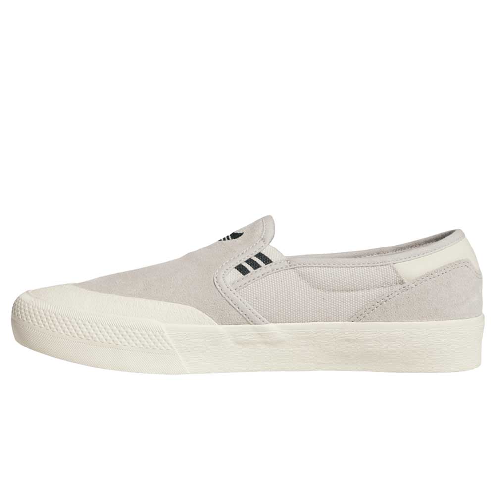 The HQ4721 Gray White Shmoofoil Slip RX Adidas Skateboarding Suede Shoes feature a light gray minimalist slip-on design with black side stripes, a white rubber sole and toe cap, inspired by classic adidas footwear.