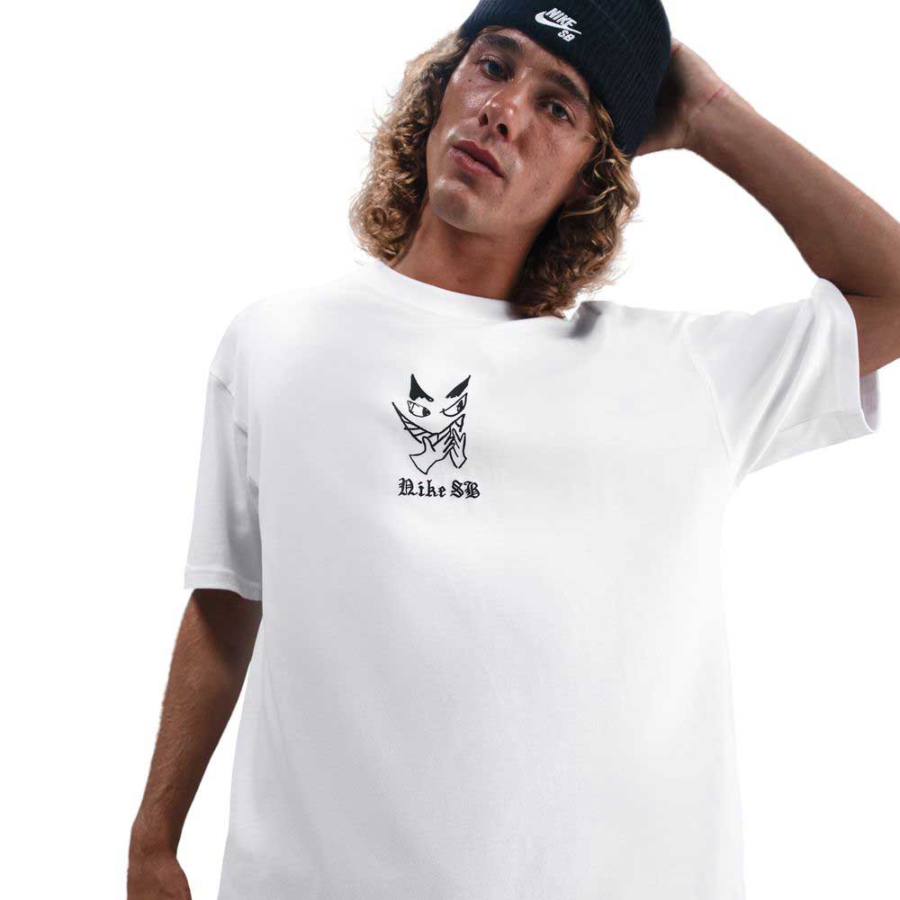 A person with long curly hair in a black Nike beanie and the HV2195100 Max 90 Skate T-Shirt SB Tee White, featuring Nike SB skateboarding screenprint, stands against a white background with one hand behind their head.