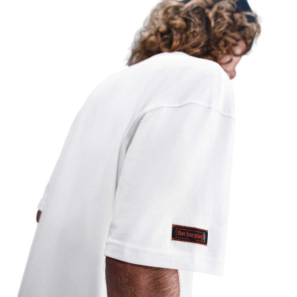 A person with curly hair wears the white Nike SB Max 90 Skate T-Shirt (HV2195100), shown from the back and side, highlighting the sleeve's small Not Supply patch. The plain white background emphasizes its durable, comfortable design.