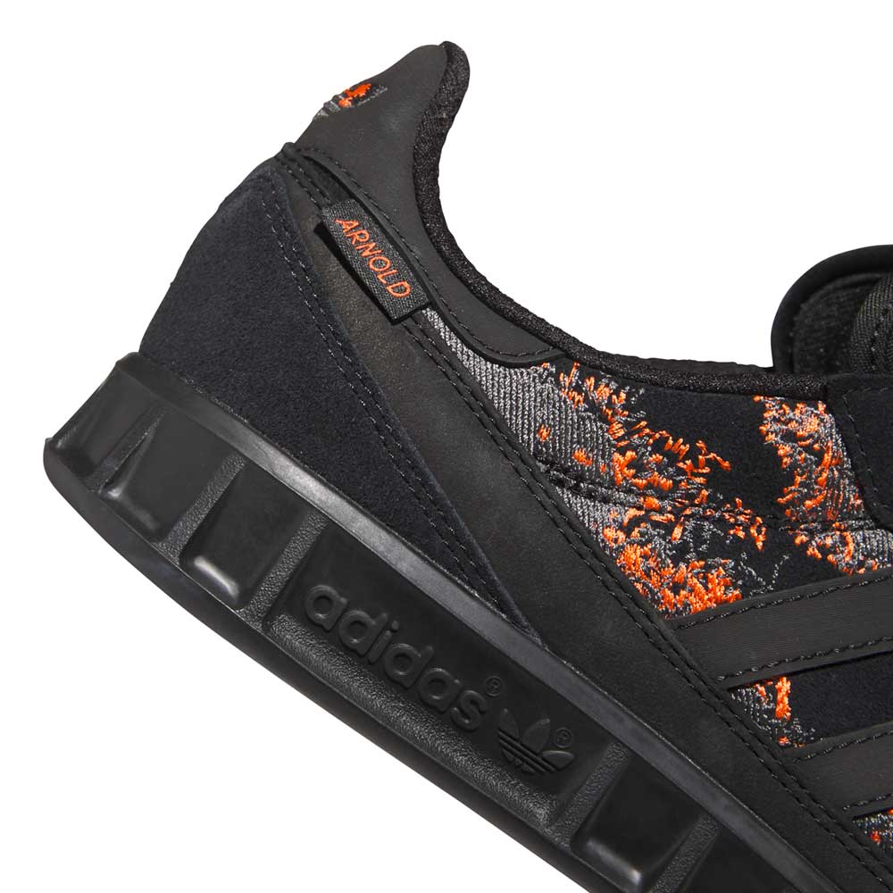 Close-up of the Handball Top x Mike Arnold Shoes Core Black Suede Adidas Skateboarding Shoes, featuring black suede and fabric, bright orange embroidery, a black rubber sole with Adidas logo, and a small AR WORLD label near the heel.