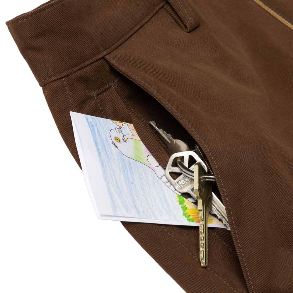 A close-up of the Hecho Por Skate Pant Anti Hero Skateboards Brown shows a pocket holding keys and a folded paper with a vibrant bird drawing—reminiscent of discoveries and exclusive finds at Skateshop Day.