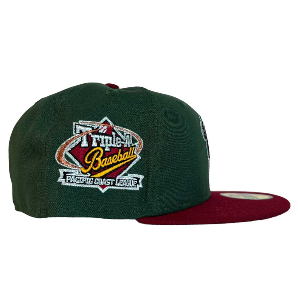 The El Sarape Sugar Land Space Cowboys New Era Hat 5950 Day is a dark green cap with a maroon brim and an embroidered Pacific Coast League logo, inspired by the team and available at Whatafitted.