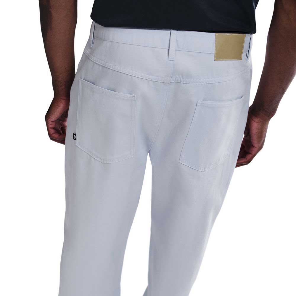 A person is shown from the back wearing light blue IB2992085 Nike SB Skate Trousers, loose fit straight leg, paired with a black shirt, highlighting the rear pockets and waistband of the pants.
