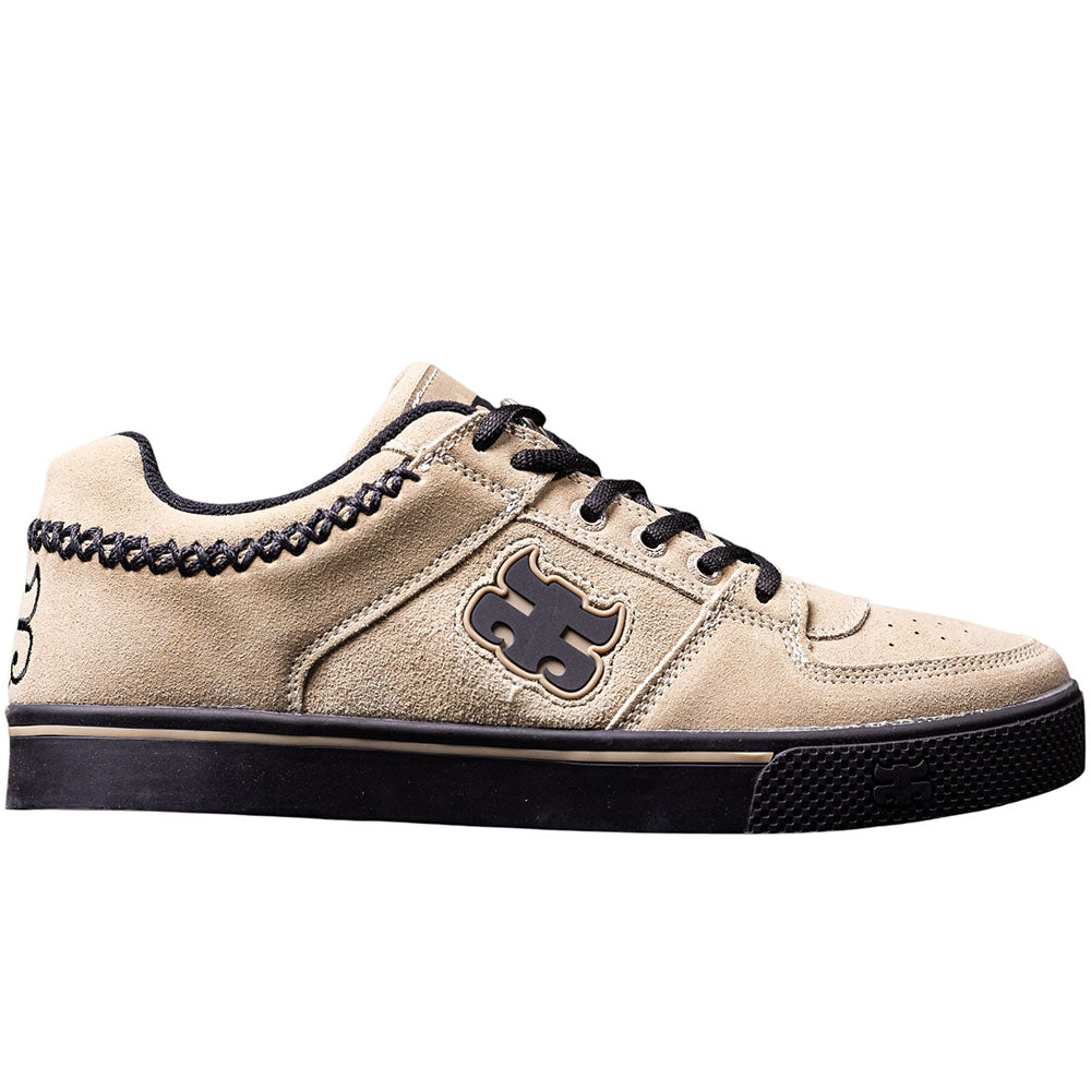 Introducing the Reed Low Natural Suede Black I Path Shoes Skateboarding—a beige natural suede skate shoe featuring black laces, a vulcanized outsole, and a distinctive black puzzle piece logo on the side. Decorative black stitching accents the top edge near the ankle for added style.