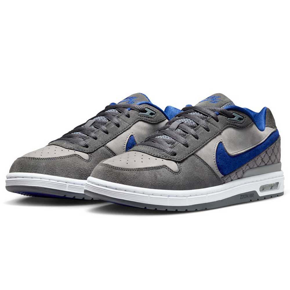 The IU7835001 Flint Grey Deep Royal Blue Paul Rodriguez Zoom Air Low Suede Skateboarding Shoes feature a gray and blue suede, mesh, and leather upper with white midsoles, gray outsoles, and Air Zoom cushioning for comfort. Blue accents highlight the design.
