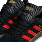 Close-up of JH8134 Black Orange Gum Busenitz Adidas Skateboarding Suede Shoes featuring black suede, orange three-stripe accents, gold Busenitz text, black laces, gold Adidas branding on the tongue, and a classic gum rubber sole.