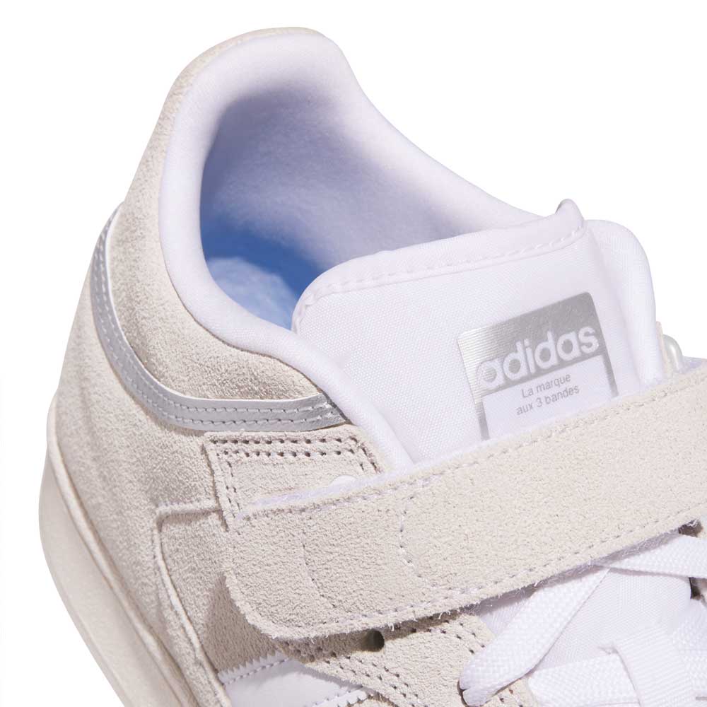 Close-up of the JH8141 White Silver White Pro Shell Mid Trainers ADV by Adidas—a skateboarding shoe with suede details, Velcro strap, gray accents, Adidas logo on the tongue, and a clean, modern design inspired by vintage basketball style.