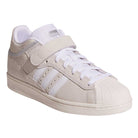 The JH8141 White Silver White Pro Shell Mid Trainers ADV by Adidas are white suede skateboarding shoes featuring beige accents, white laces, a Velcro strap, signature three stripes, vintage basketball style, rubber toe cap, and flat outsole.