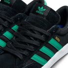 Close-up of JH8143 Nora Black Green Suede Adidas Skateboarding Shoes featuring green three stripes, black tongue with green Adidas logo, gold "HORA" text honoring Nora Vasconcellos, and white midsoles.
