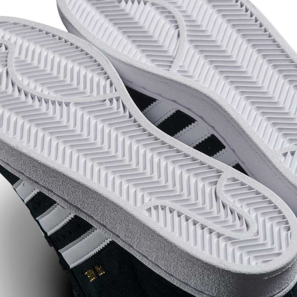 Close-up of two JH8146 Black White Gold Suede Pro Model ADV Adidas Skateboarding Shoes stacked sole-to-sole, highlighting thick white herringbone-patterned soles and black suede uppers with white stripes and gold detailing.