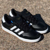 A pair of JI 0846 Black White Gum Tyshawn 2 II Adidas Skateboarding Leather Suede Shoes, with classic white stripes and soles, rests on a rough, sunlit surface.