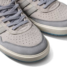 Close-up of two JI0848 Granite White Tyshawn 2 II Adidas Skateboarding Leather Suede Shoes, featuring perforated toes, gray laces, white midsoles, and subtle side stripes, displayed on a white background.