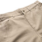Close-up of the JM5832 Gray Clay Kader Sylla Pant from Adidas, featuring a straight-leg fit, waistband, front pockets with rivets, belt loops, and a button closure.