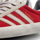 Close-up of JP5861 Red White Gold Gazelle ADV Adidas Skateboarding suede shoes featuring red uppers, white stripes and laces, gold GAZELLE lettering on the side, and a textured white rubber sole for classic style.