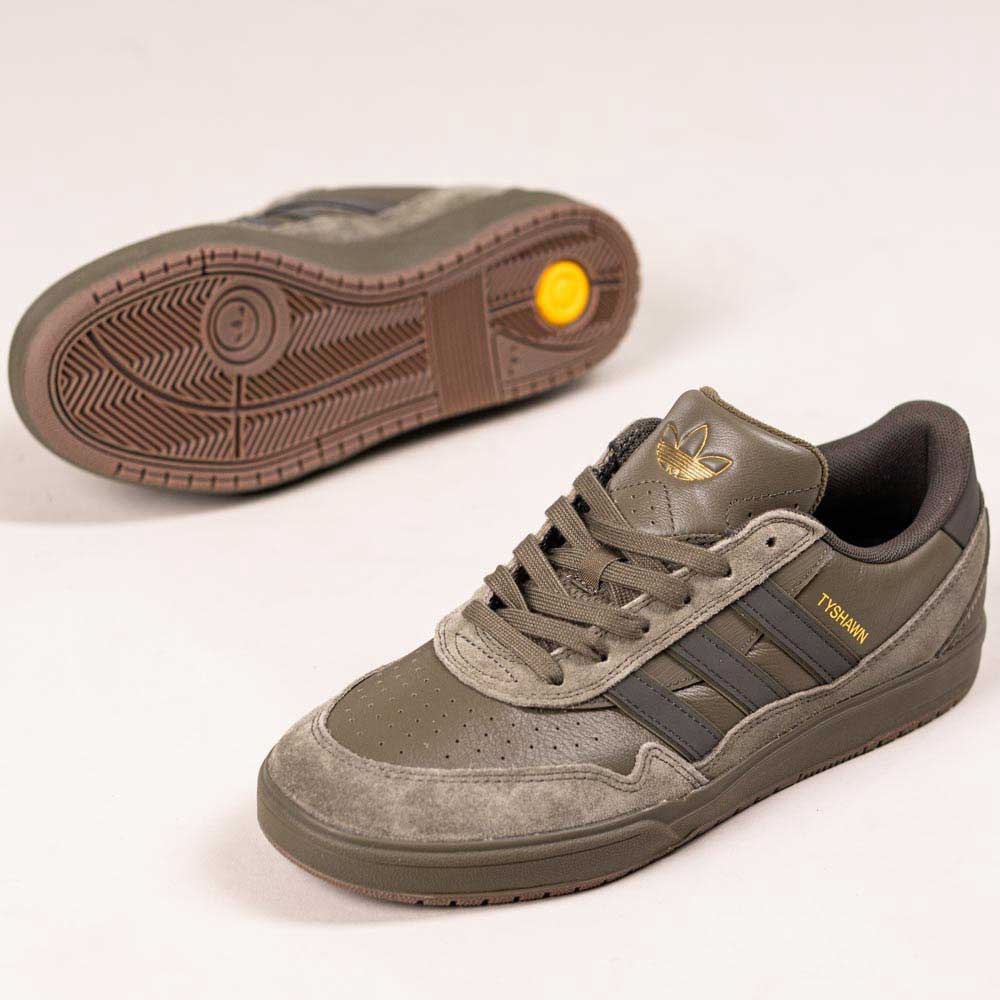 The JQ1132 Olive Strata Shadow Olive Tyshawn 2 II Adidas Skateboarding Shoes feature olive and gray hues, premium leather and suede, a Lightstrike midsole, gold side branding, and a yellow circular detail on the sole.