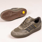 The JQ1132 Olive Strata Shadow Olive Tyshawn 2 II Adidas Skateboarding Shoes feature olive and gray hues, premium leather and suede, a Lightstrike midsole, gold side branding, and a yellow circular detail on the sole.
