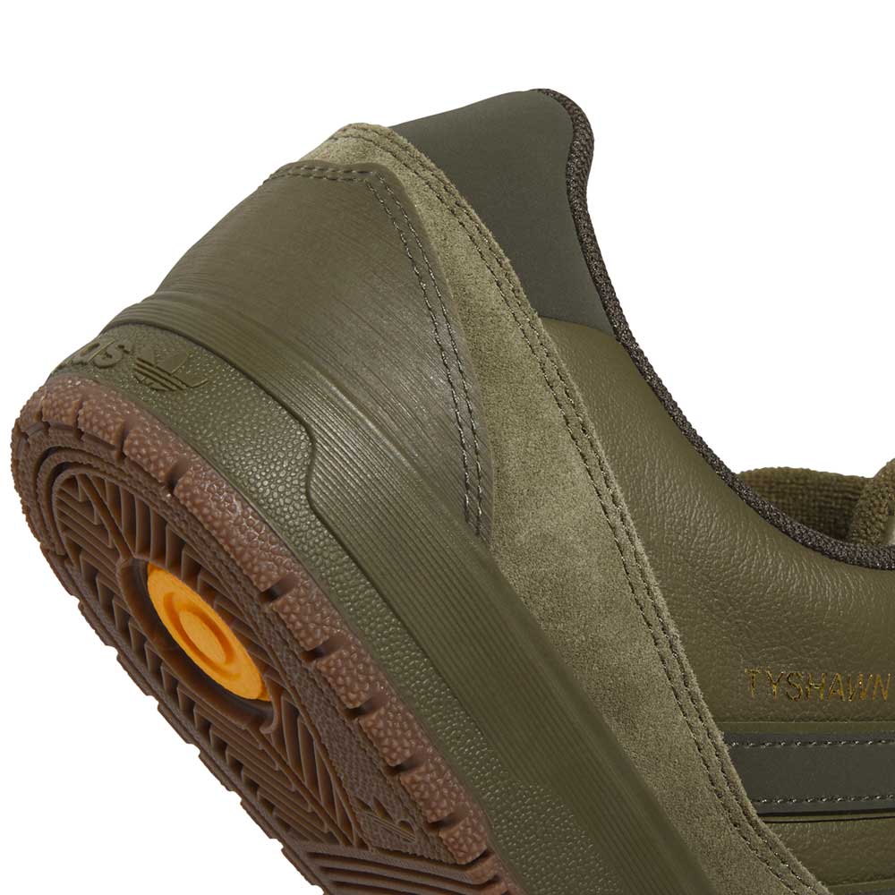 Close-up of the back and side of the JQ1132 Olive Strata Shadow Olive Tyshawn 2 II Adidas Skateboarding Shoes, featuring suede and premium leather textures, a brown sole, Lightstrike midsole, and TYSHAWN in gold on the side.