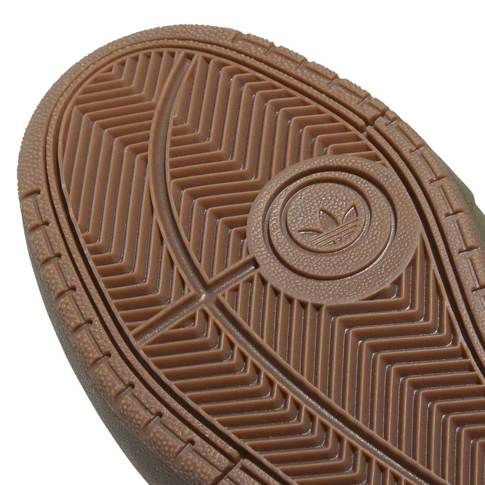 Close-up of the brown rubber sole of the JQ1132 Olive Strata Shadow Olive Tyshawn 2 II Adidas Skateboarding Shoes, showing a circular trefoil logo, detailed herringbone tread for grip, and Lightstrike midsole cushioning for comfort.