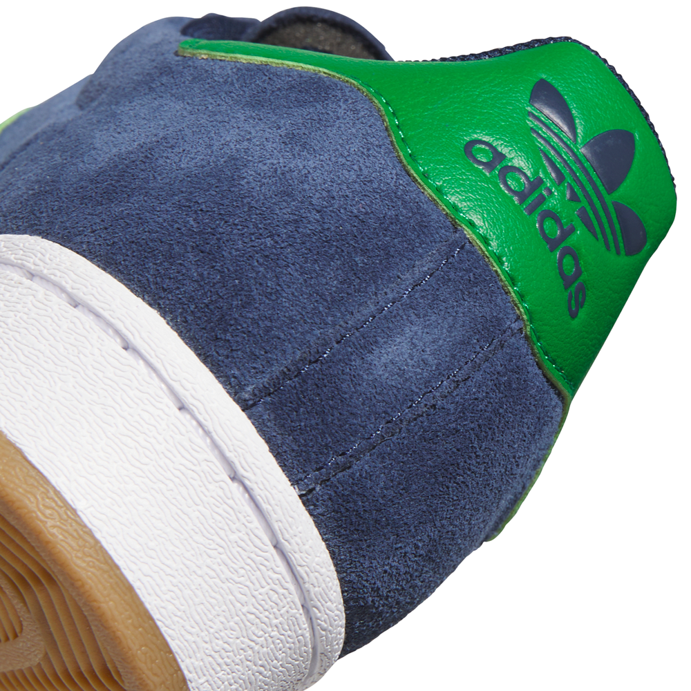 Close-up of the heel on the JQ2098 Navy Green White Superstar ADV Adidas Suede Skateboarding Shoes, showing blue suede, green leather with trefoil logo, durable cupsole, white midsole, and brown rubber outsole.
