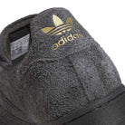Close-up of the heel of the JR7409 Carbon Purple Superstar ADV Adidas Suede Skateboarding Shoes, with gold Adidas trefoil logo and branding on the back, inspired by the classic Superstar ADV design.