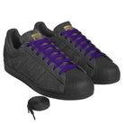 A pair of JR7409 Carbon Purple Superstar ADV Adidas suede skateboarding shoes with textured uppers, gold tongue labels, purple laces, and an extra set of black shoelaces placed in front.