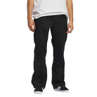 A person is standing against a white background, shown from shoulders down, wearing a white T-shirt, JX6827 Black Kader Sylla Pant Adidas, and black-and-white sneakers.