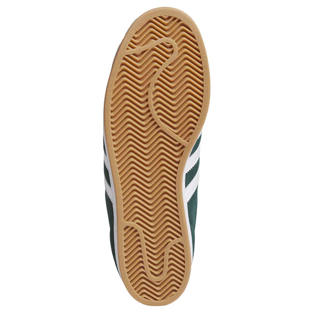 The image shows the gum rubber sole of the KI5732 Green White Superstar ADV Adidas Skateboarding Suede Shoes, featuring a herringbone tread, a circular grip near the toe, and white and dark green accents on the upper.