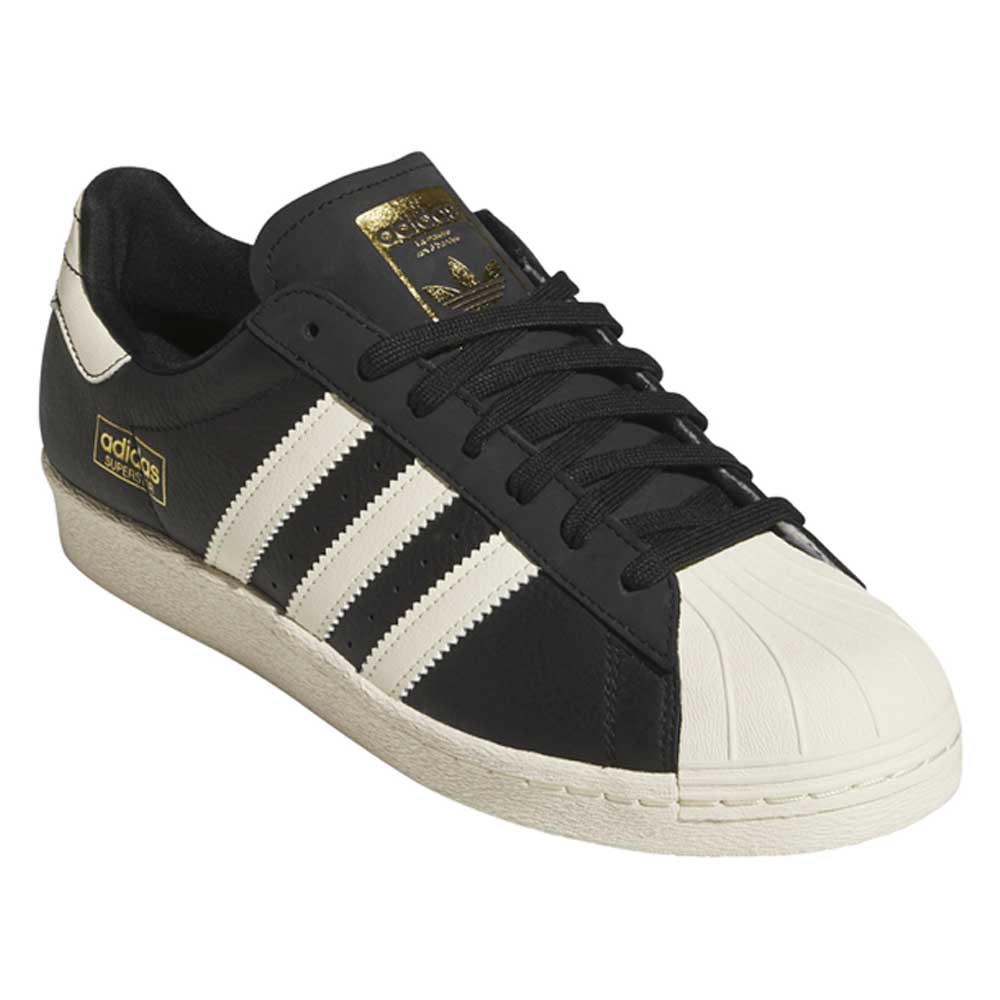 The KK5003 Black White Superstar 80 ADV Adidas Skateboarding Leather Shoes feature three white stripes, gold tongue and heel accents, and a white textured rubber toe cap for a redefined classic skateboarding look.