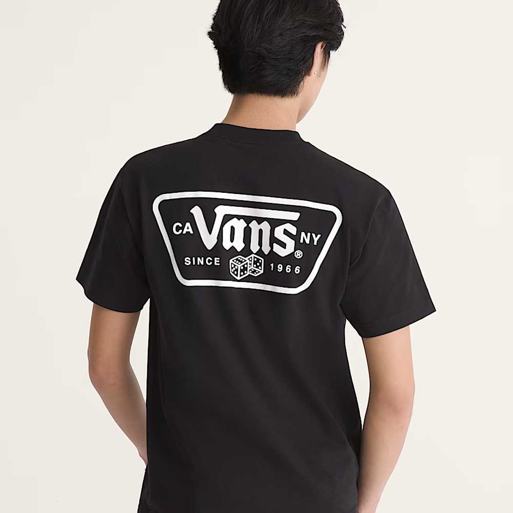 A person with short dark hair, seen from behind, wears a loose-fit black Vans Skateboarding Knu Patch VN000WU8BLK1 short sleeve tee with a white Vans logo and "CA NY Since 1966" text on the back.