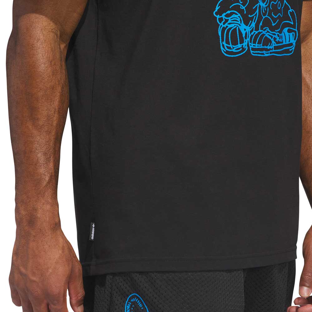 A close-up of a person wearing the Kogan Dog Tee Black Blue KC6304 from Adidas Skateboarding, featuring a blue outline dragon graphic, paired with black shorts. Only the arms and torso are visible, capturing skate culture style.