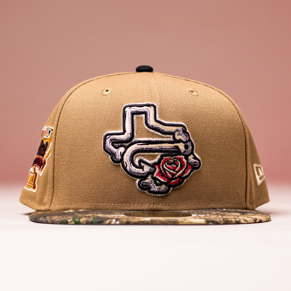 The La Ofrenda Khaki RTC Copa Corpus Christi Hooks New Era 5950 Fitted hat features a Texas bone design patch with a red rose, camo brim, and unique side patches—an eye-catching Space Cowboys piece set against a pink background.