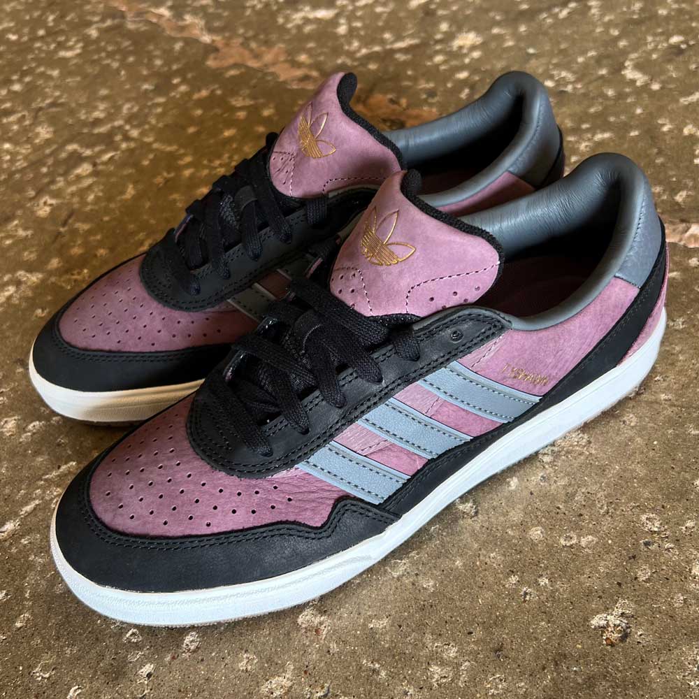 The Lavandar Gray Black Tyshawn 2 II Adidas Skateboarding Leather Suede Shoes feature purple suede uppers, black laces, gray Adidas stripes, and white soles, styled for skateboarding culture and shown on a rugged brown concrete surface.