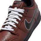 Close-up of the HJ4131-200 Limosine Dark Pony Black Silver White Nike SB Dunk Low Pro, featuring brown textured leather, white laces, a black tongue label, silver-outlined black Swoosh, black sole, and inner lining.